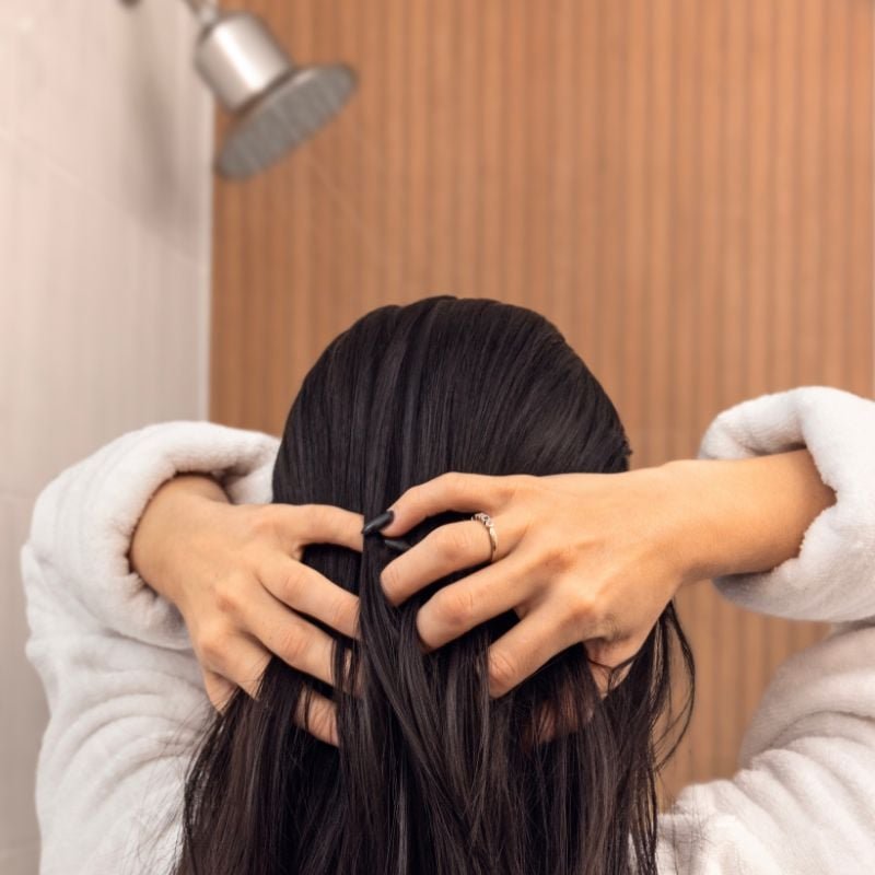 Person with long hair massaging scalp in the shower.